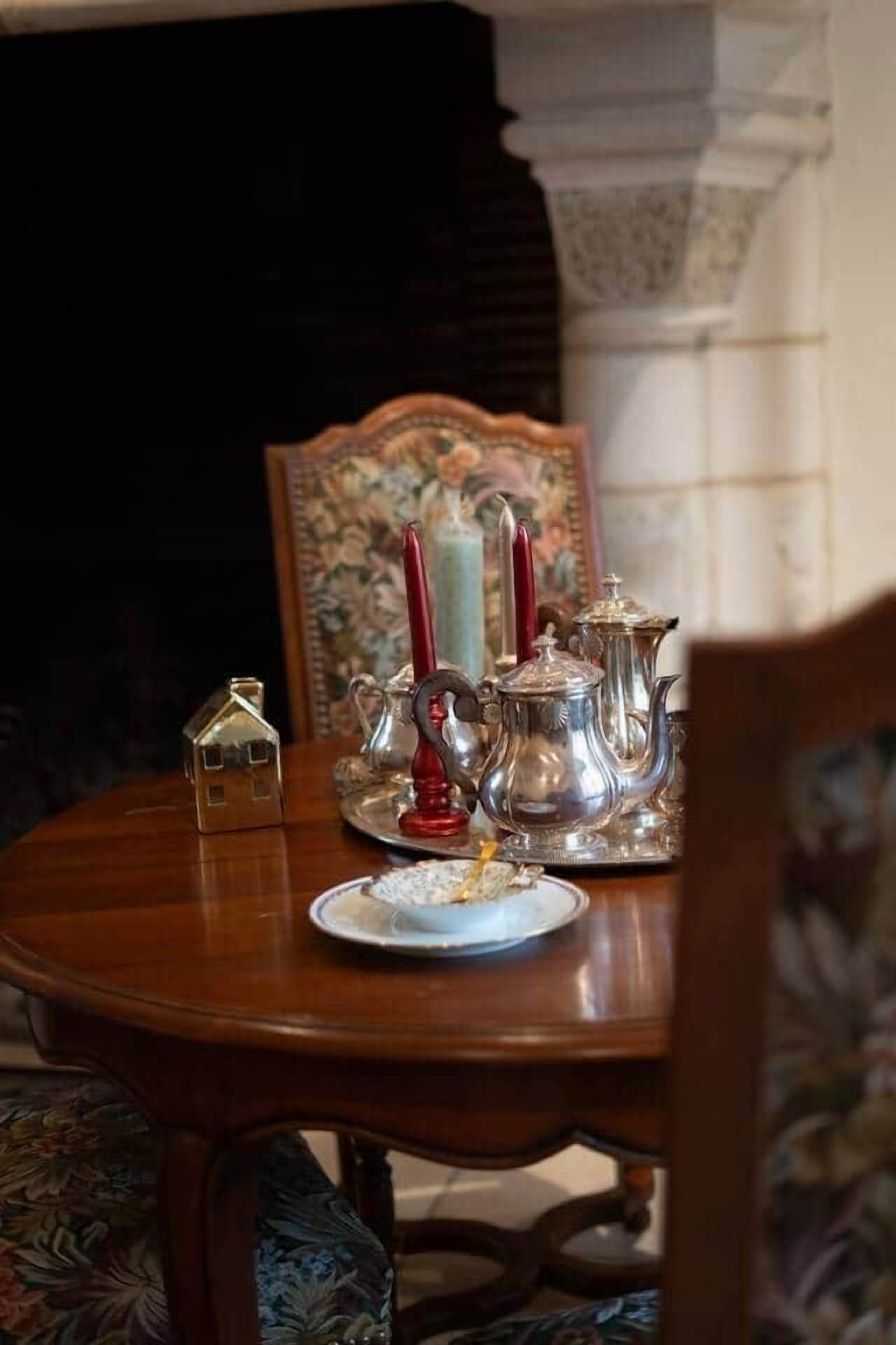 Een eettafel met bestek, een theepot en een kaars.