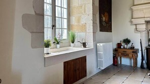 Habitación con pared de piedra, ventana con vistas, radiador, armario de madera y una pintura.