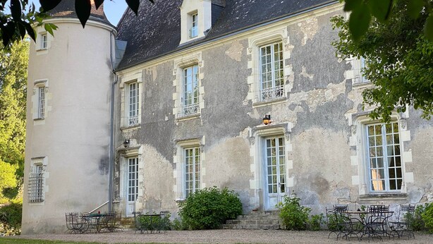 Un edificio histórico con una torre, numerosas ventanas y una entrada principal con escalones.
