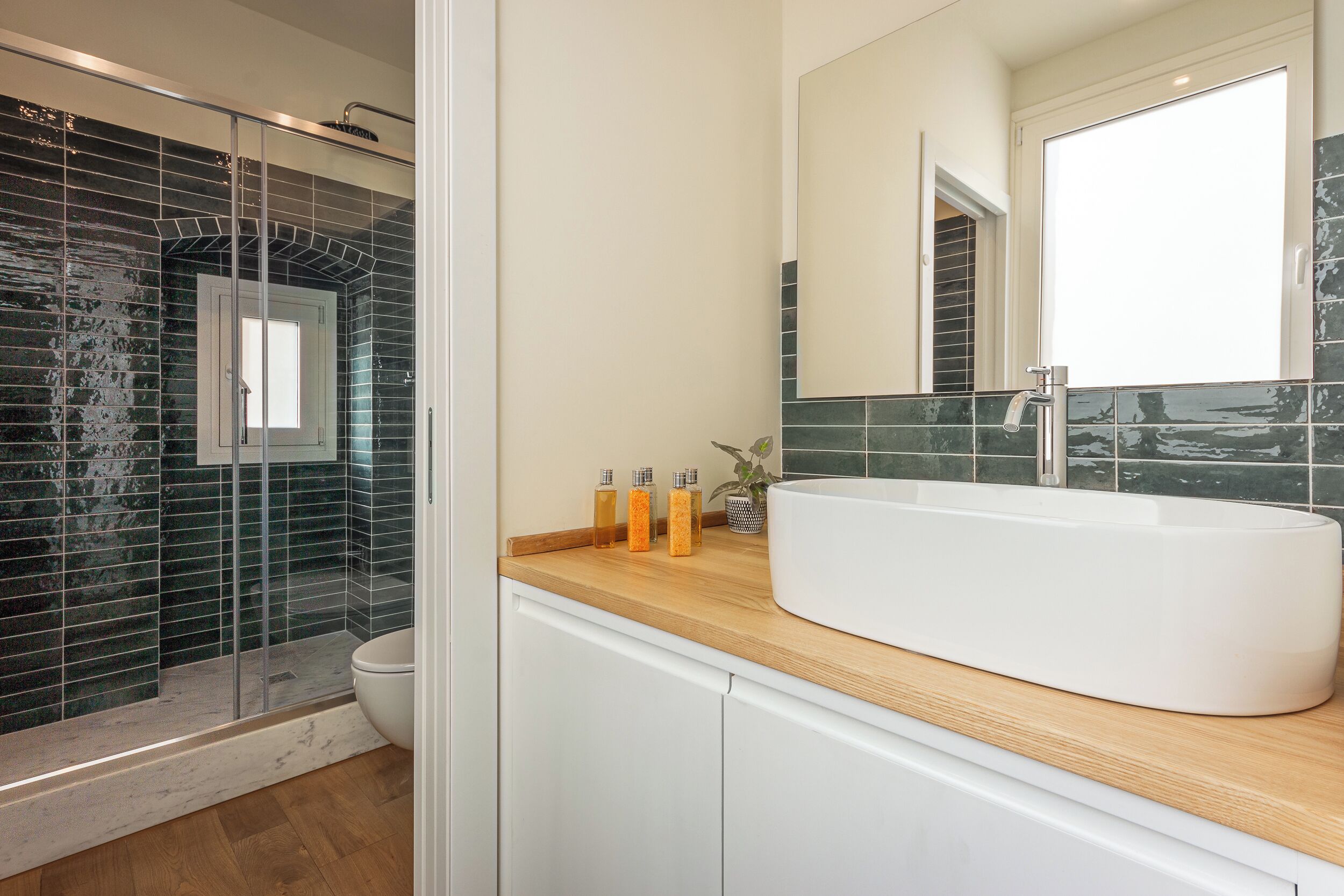A modern bathroom with a large white sink, a glass shower enclosure, and a wooden countertop.