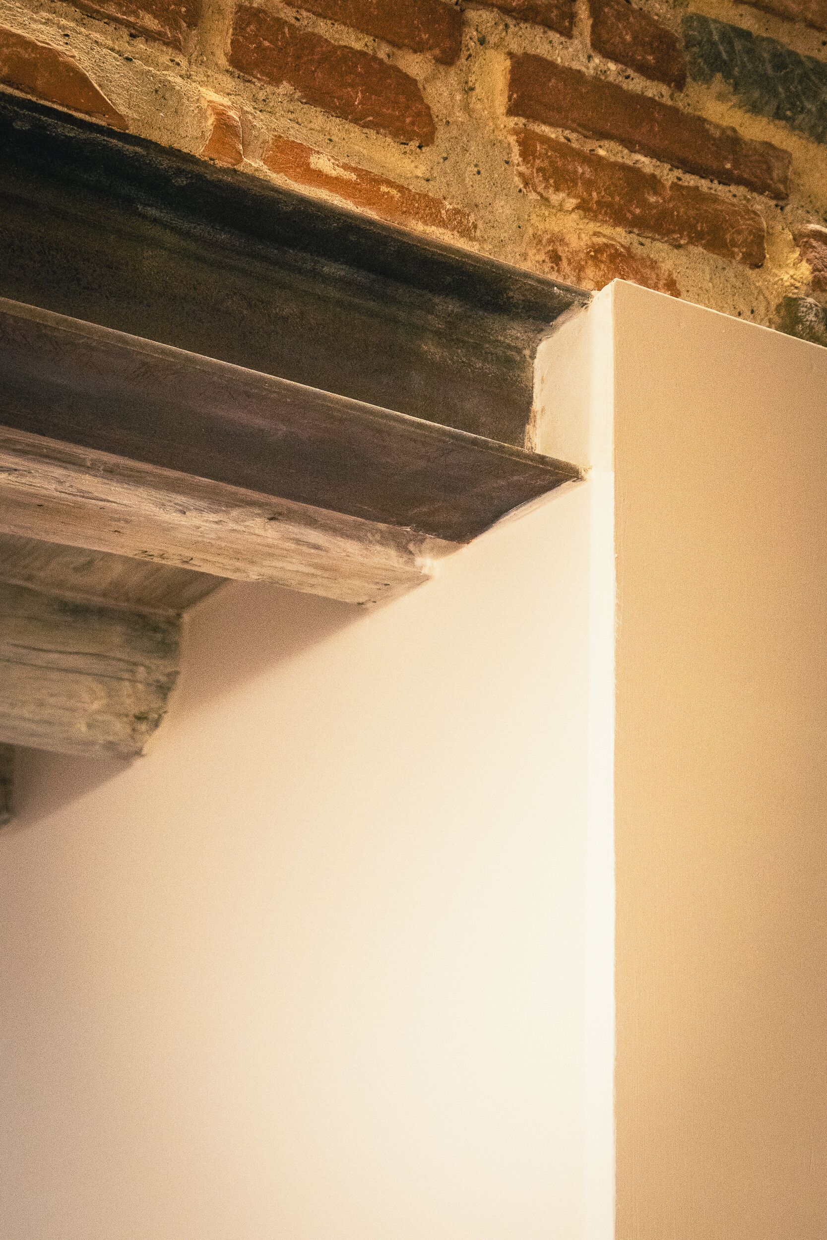 A corner of a room with a white wall and a brick wall.