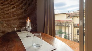 Un balcon donnant sur un mur de briques et un toit recouvert de tuiles.