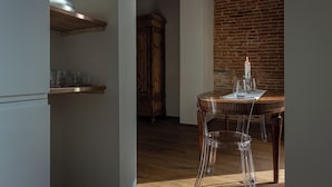 Un espace repas avec une table en bois, des chaises transparentes et un mur en briques.