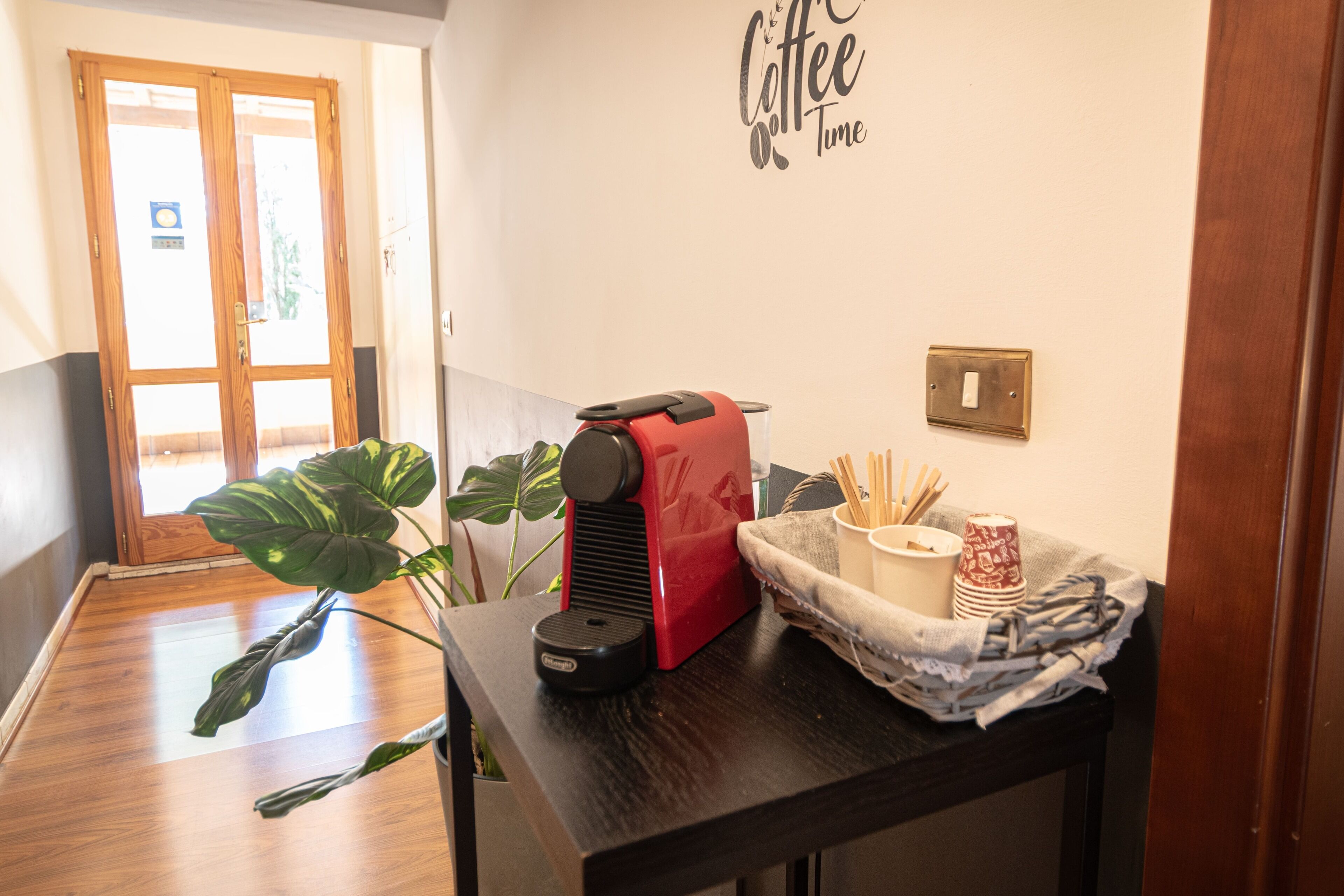 Un coin cuisine équipé d’une machine à café, d’une plante et d’un panneau mural indiquant « Pause café ».