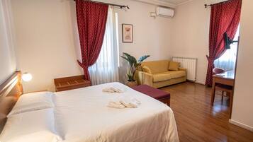 Una habitación de hotel con cama, sofá, mesa y planta.