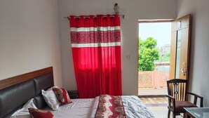 Ein Hotelzimmer mit Bett, Sessel, Tisch und Blick ins Freie.