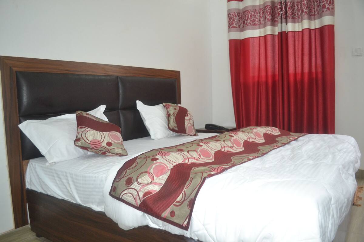 Una cama con cabecera de madera, ropa de cama blanca y una manta decorativa.