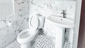 A bathroom with a toilet, sink, and marble walls.