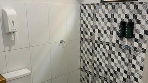 Un baño con inodoro, secamanos, ducha y pared de azulejos con diseño a cuadros.