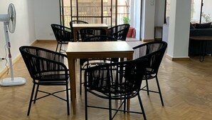 A spacious room with a wooden herringbone floor, a central table with chairs, and a ceiling fan. - Pyramids Nights Hostel (Giza)