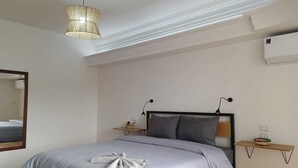 A bedroom with a bed, bedside tables, a hanging light fixture, a mirror, and an air conditioning unit. - Pyramids Nights Hostel (Giza)