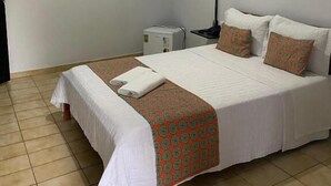 Hotellihuone, jossa on sänky, yöpöytä, lamppu ja kattovalaisin.
