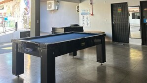 Sisätiloissa sijaitseva biljardipöytäalue, jossa on metallikatto, ilmanvaihtojärjestelmä ja ovi, joka johtaa ulos.