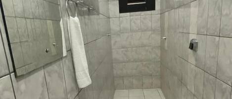 Un baño pequeño y moderno con un lavamanos blanco, inodoro y un cubo de basura negro.