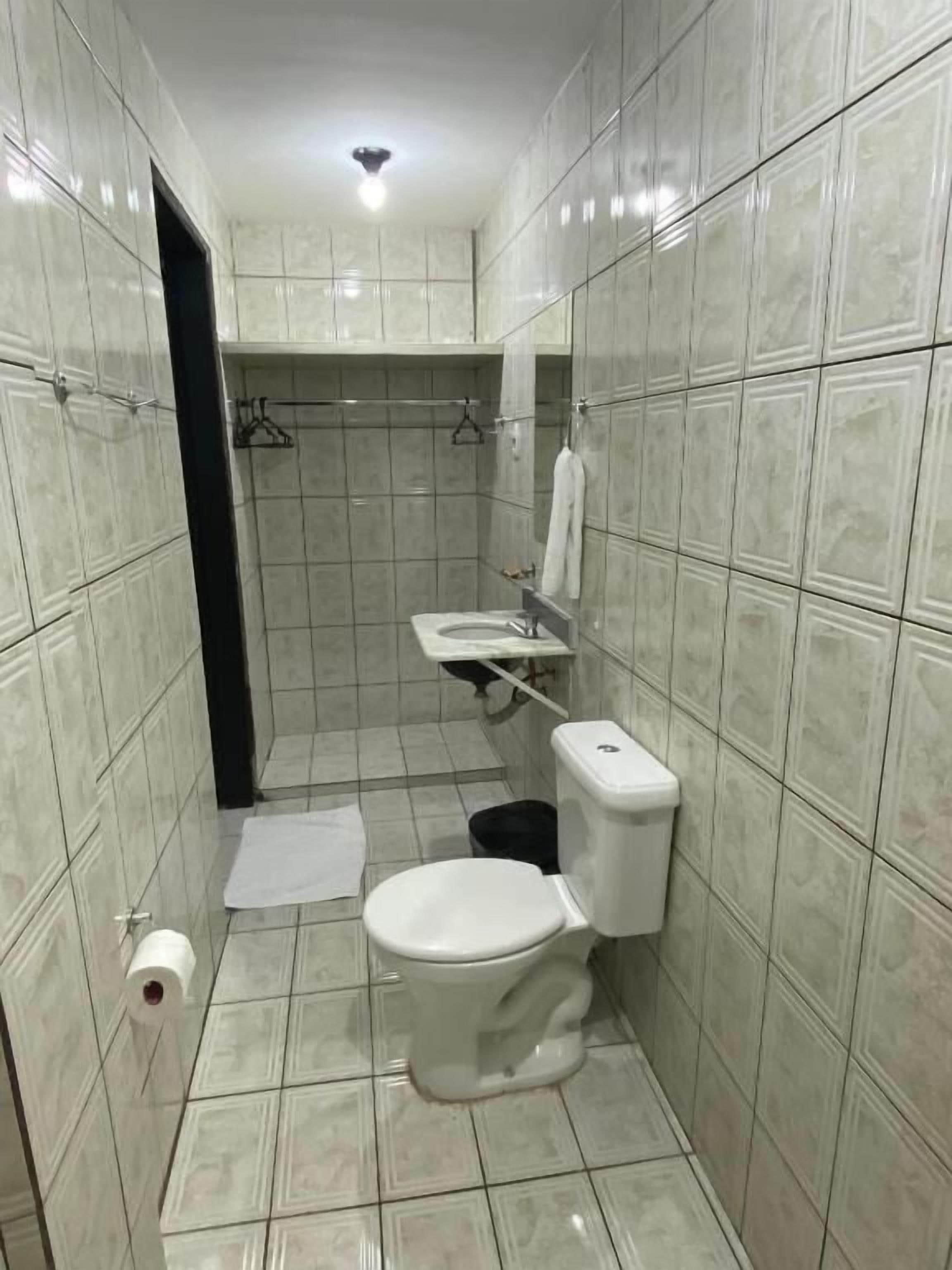 Un baño pequeño con azulejos, que incluye inodoro, lavabo y zona de ducha.