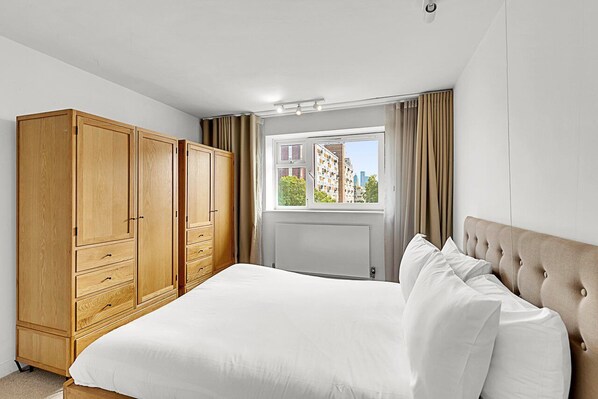 Un dormitorio con una cama grande, un armario de madera y una ventana con cortinas.