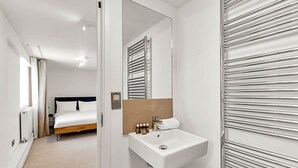Une chambre d’hôtel avec un lit, un lavabo blanc et un miroir.
