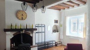A living room with a fireplace, a red armchair, a clock, and hanging lights. - Vitis Vinifera, Pour une escapade œnologique en famille (Deux Rivières)