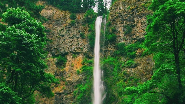 A waterfall cascading down a rocky cliff, with a bridge spanning across the water.
