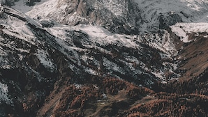 A mountainous landscape with snow-covered peaks and a valley with dense forest.