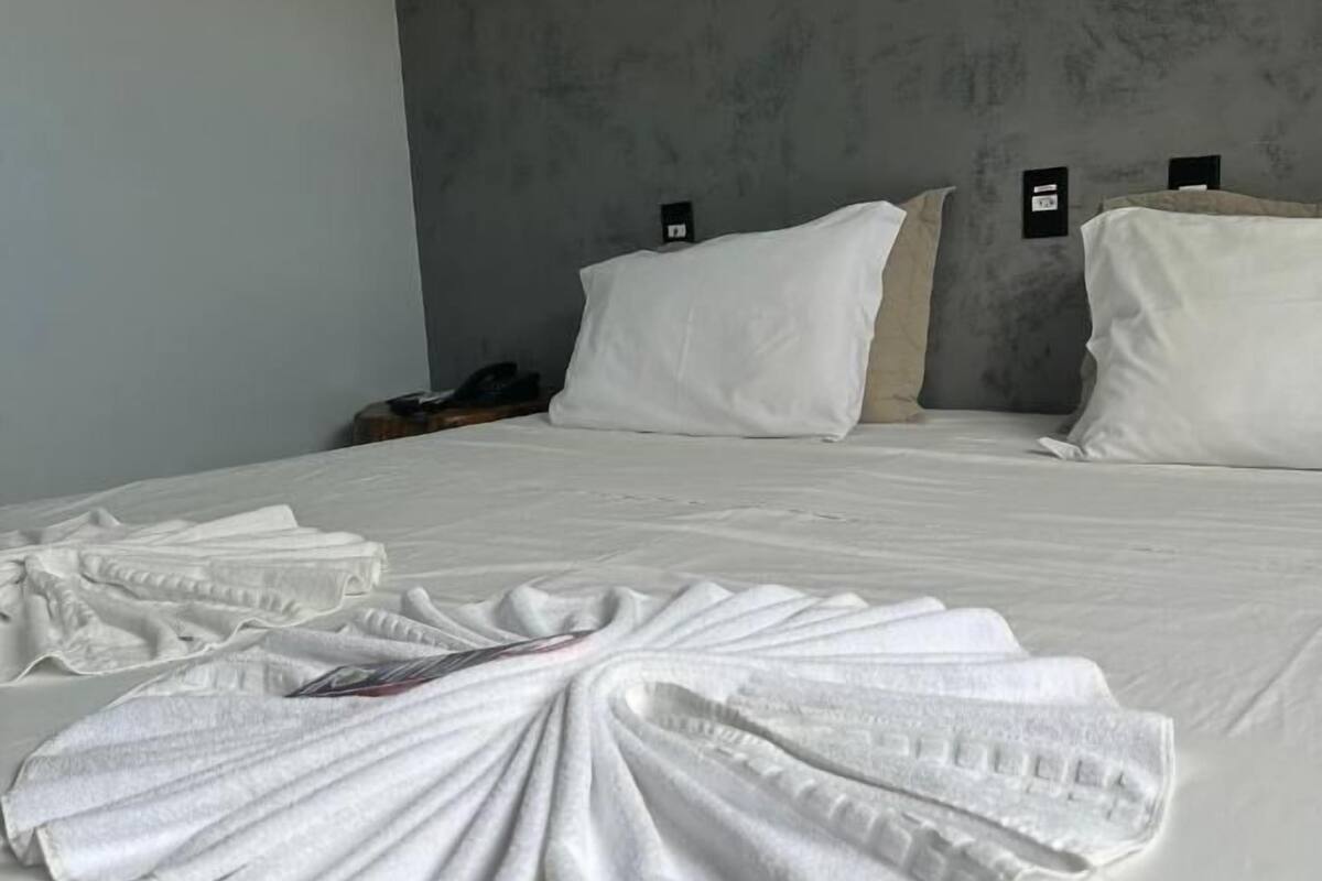 Een opgemaakt bed met witte lakens en een handdoek gevouwen in de vorm van een waaier.