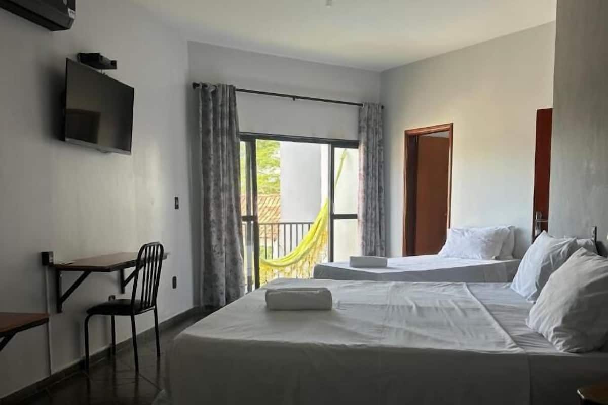 Hotelkamer met twee bedden, een bureau, een stoel, een televisie en een balkon met uitzicht.