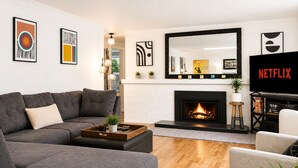 A modern living room with a fireplace, a sofa, a coffee table, and a TV displaying the Netflix logo.