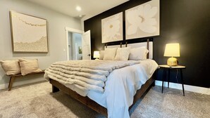 Camera da letto con un letto grande, un comodino con una lampada e due quadri di fiori appesi al muro.