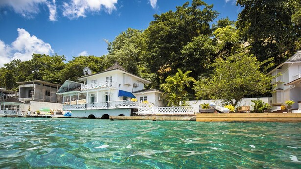 A waterfront property with a house, a dock, and clear blue water. - LillyBelleMar,San San Port Antonio,with pristine views and world class amenities (Fairy Hill)
