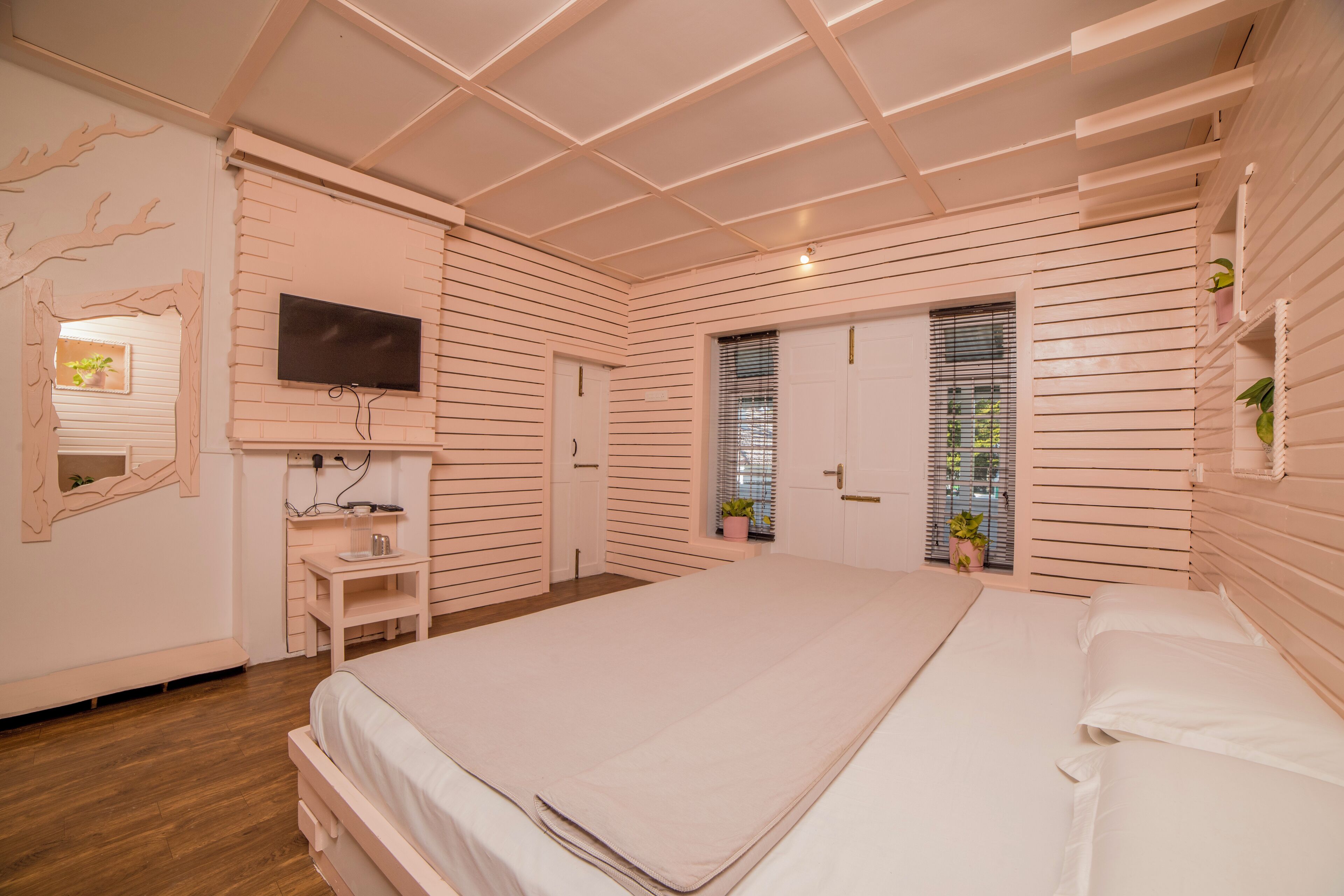 Een slaapkamer met een groot bed, een aan de muur bevestigde televisie en een schuifdeur naar een andere kamer.