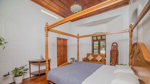 Una cama con dosel, un tablero de noche pequeño y una planta en maceta.