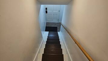 A staircase with a wooden handrail leading to a white door at the top.
