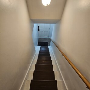 A staircase with a wooden handrail leading to a white door at the top. - 2 bedrooms that are warm and comfortable queen size beds

 (Williston)