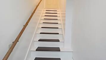 Eine Treppe mit weißen Stufen und dunklen Wangen, die zu einer Tür oben führt.