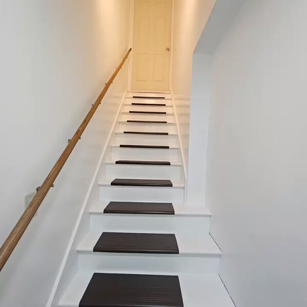 A staircase with white steps and dark risers, leading to a door at the top.