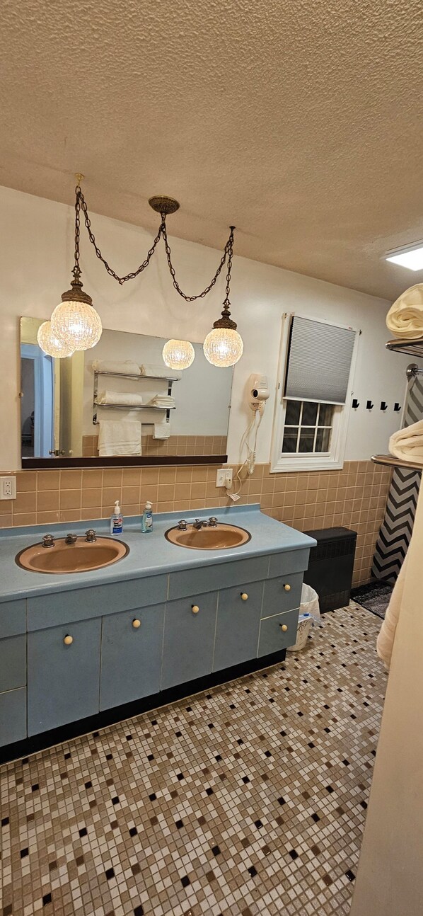 A bathroom with two sinks, a mirror, and a chandelier. - 2 bedrooms that are warm and comfortable queen size beds

 (Williston)