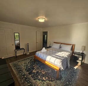 A bedroom with a bed, a nightstand, a lamp, a bench, and a door. - 2 bedrooms that are warm and comfortable queen size beds

 (Williston)