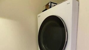 Un appareil combiné lave-linge et sèche-linge LG à chargement frontal, à deux portes et conçu pour être fixé au mur.