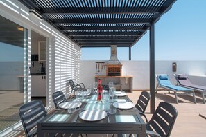 An outdoor patio with a table set for dining, a grill, and lounge chairs. - Casa Afortunada, the pleasure of relaxation (Costa Teguise)