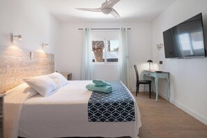 A hotel room with a bed, a desk, a chair, a TV, and a window with curtains. - Casa Afortunada, the pleasure of relaxation (Costa Teguise)