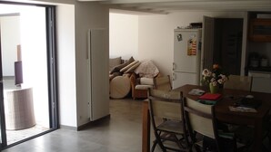 Una cocina moderna con comedor, un conjunto de sofás y un amplio ventanal corredero que da a un espacio exterior.