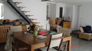 Un comedor con una mesa de madera, sillas, un jarrón con flores y una escalera que lleva a otra habitación.
