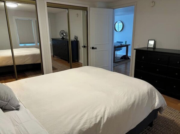 A bedroom with a bed, a dresser, and a mirror on the wall. - Colchester Lake House (Colchester)
