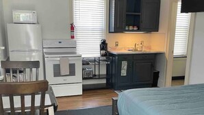 A compact room with a bed, a desk, a kitchenette, and a TV. - Cozy Studio 1/2 block to Church St & Shops-Pets (Burlington)