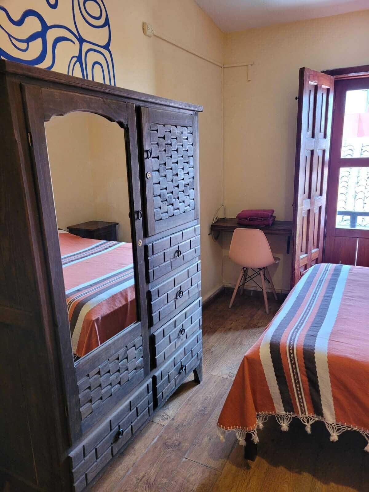 A room with a bed, a wardrobe, a desk, and a chair.