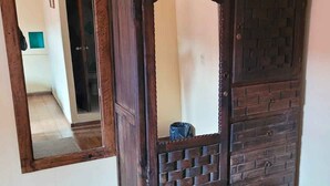 A wooden cabinet with a mirror, a framed picture, and a small trash bin.