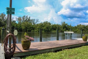 A wooden dock with a table and chairs, a hose, and two potted plants. -  Attached Studio retreat with walking distance to the Dock 🐠 (Everglades City)