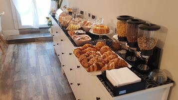 A breakfast buffet with pastries, bread, and cereal options.