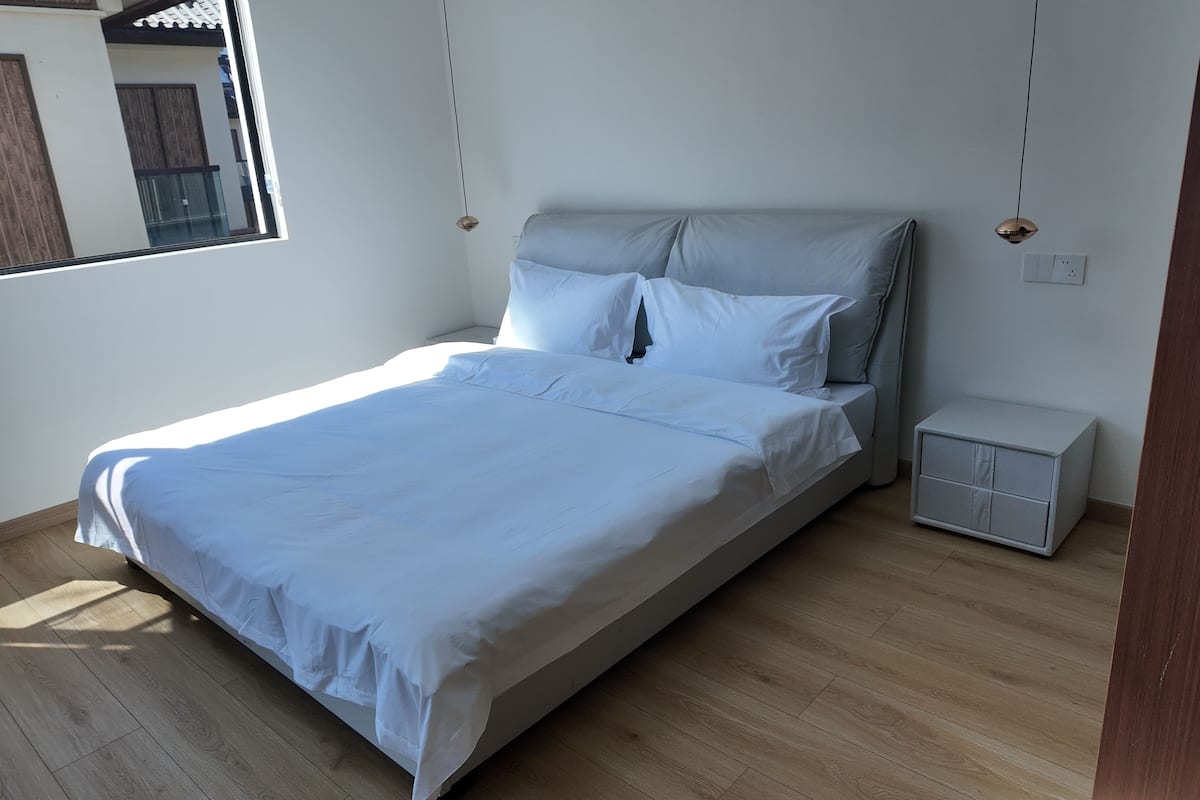 A bedroom with a bed, a nightstand, and a window.
