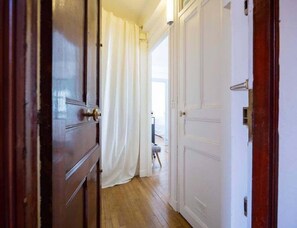 A hallway with wooden doors and white curtains.